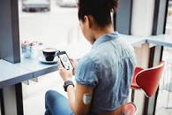 A person sitting at a table looking at a phone